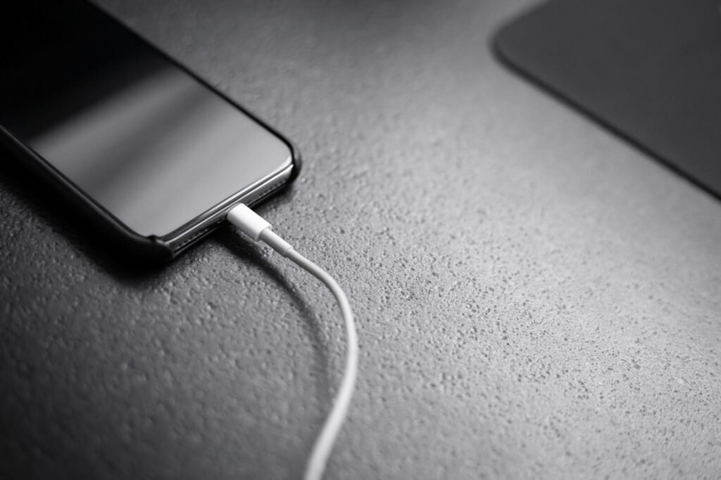 iPhone plugged in and charging on a dark surface